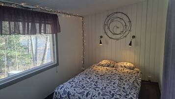 Une chambre à coucher avec un lit, une fenêtre avec des rideaux, des guirlandes lumineuses et des lampes fixées au mur.