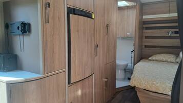 A compact, well-organized room with a bed, a toilet, and a kitchenette area.