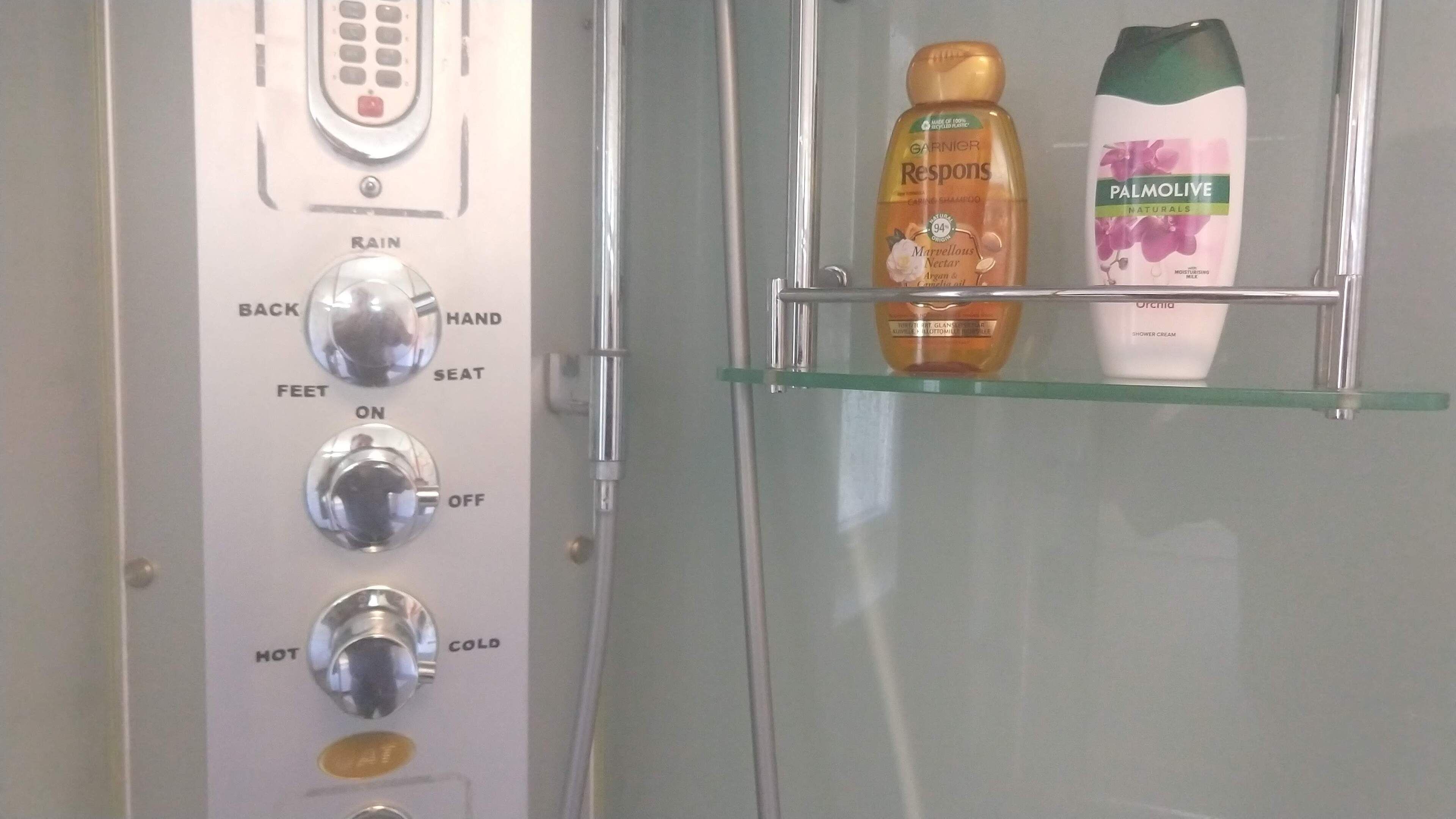 Un panneau de commande de douche offrant différentes options : jet pluie, pommeau de douche, jet massant pour le dos et les pieds, et réglage de la température.