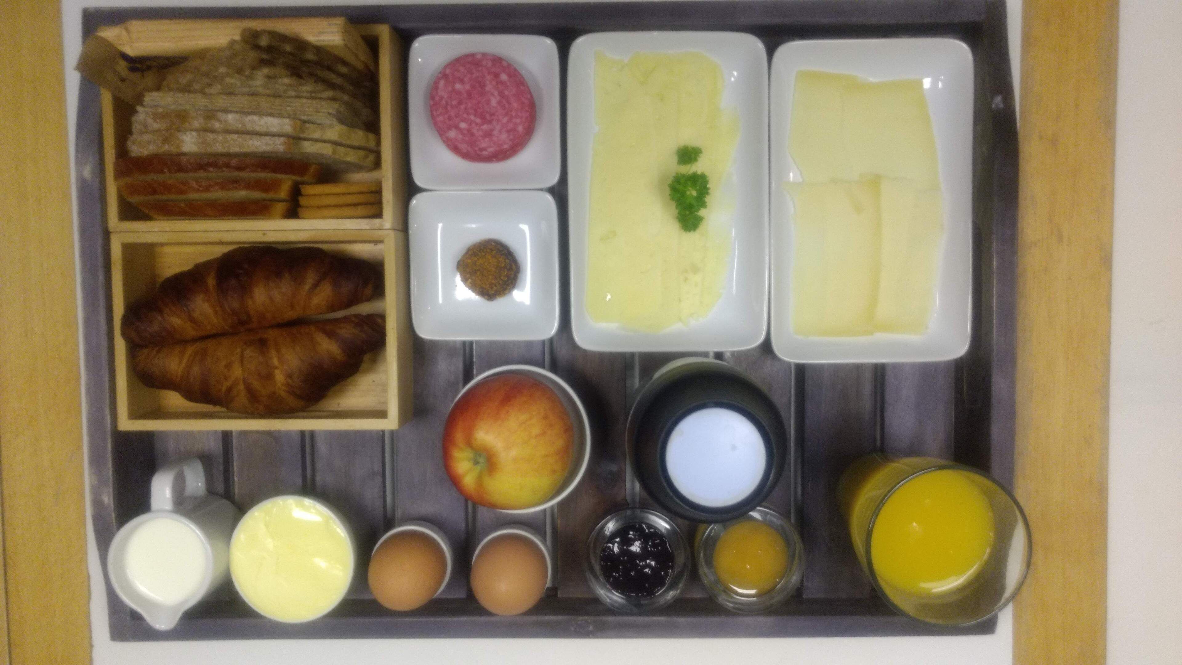 Ein Frühstückswagen mit Croissants, Schinken, Käse, Eiern und verschiedenen Aufstrichen.