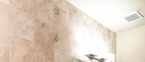A bathroom with beige tiles, a white toilet, a wooden vanity with a sink, and a large mirror.