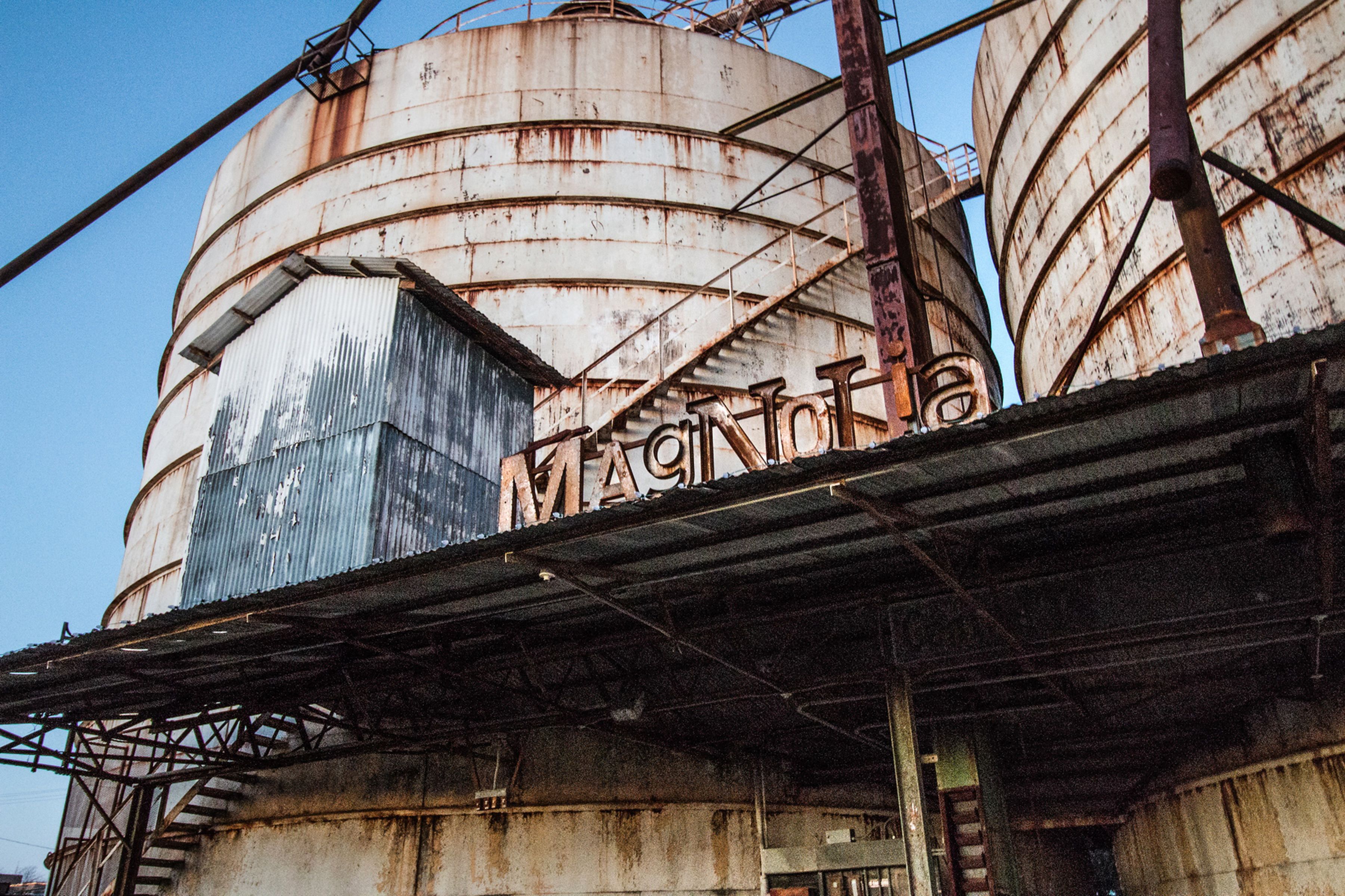 A large industrial building with multiple cylindrical tanks and a corrugated metal roof.