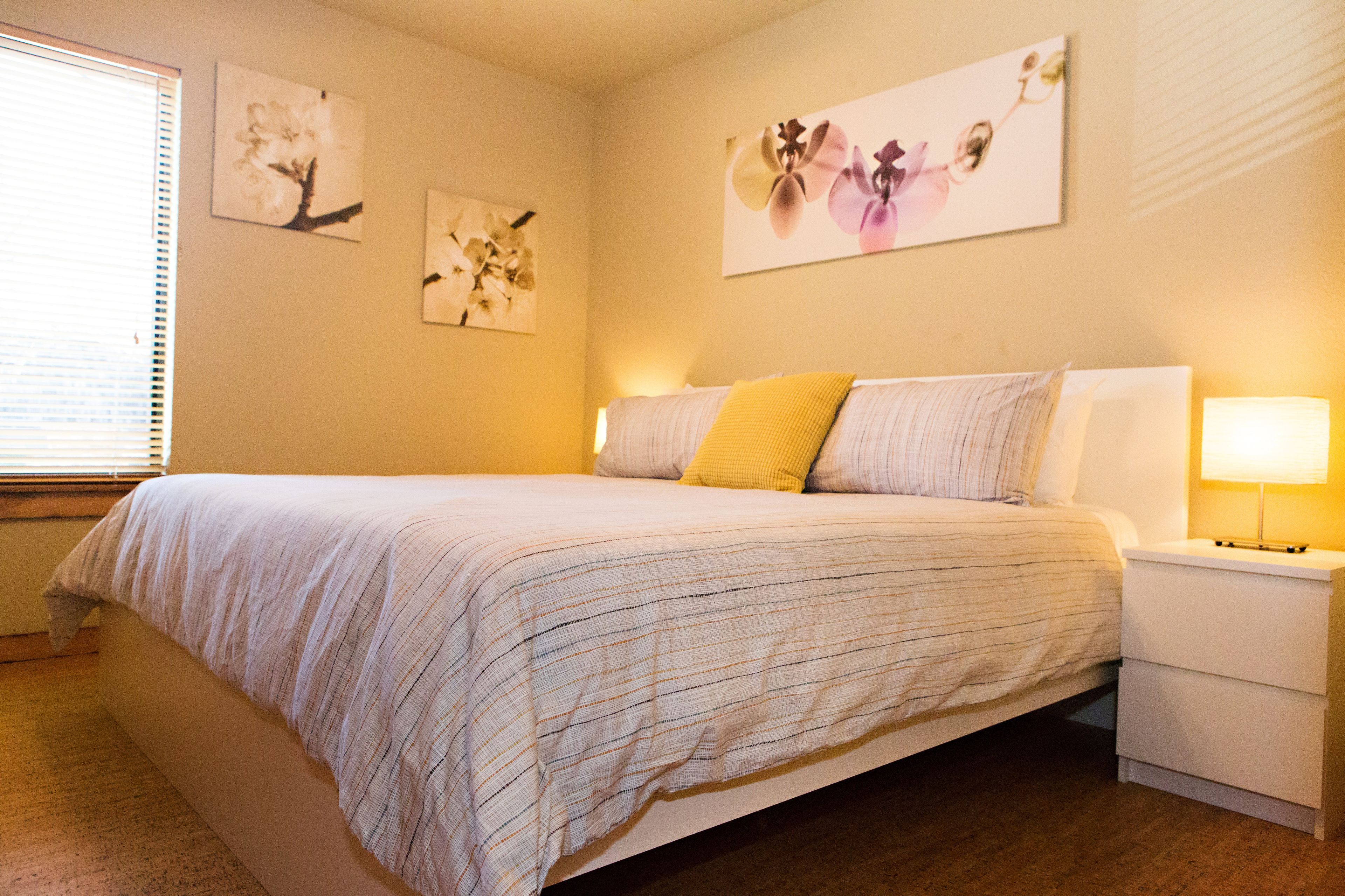 A bedroom with a bed, a nightstand, and wall art.