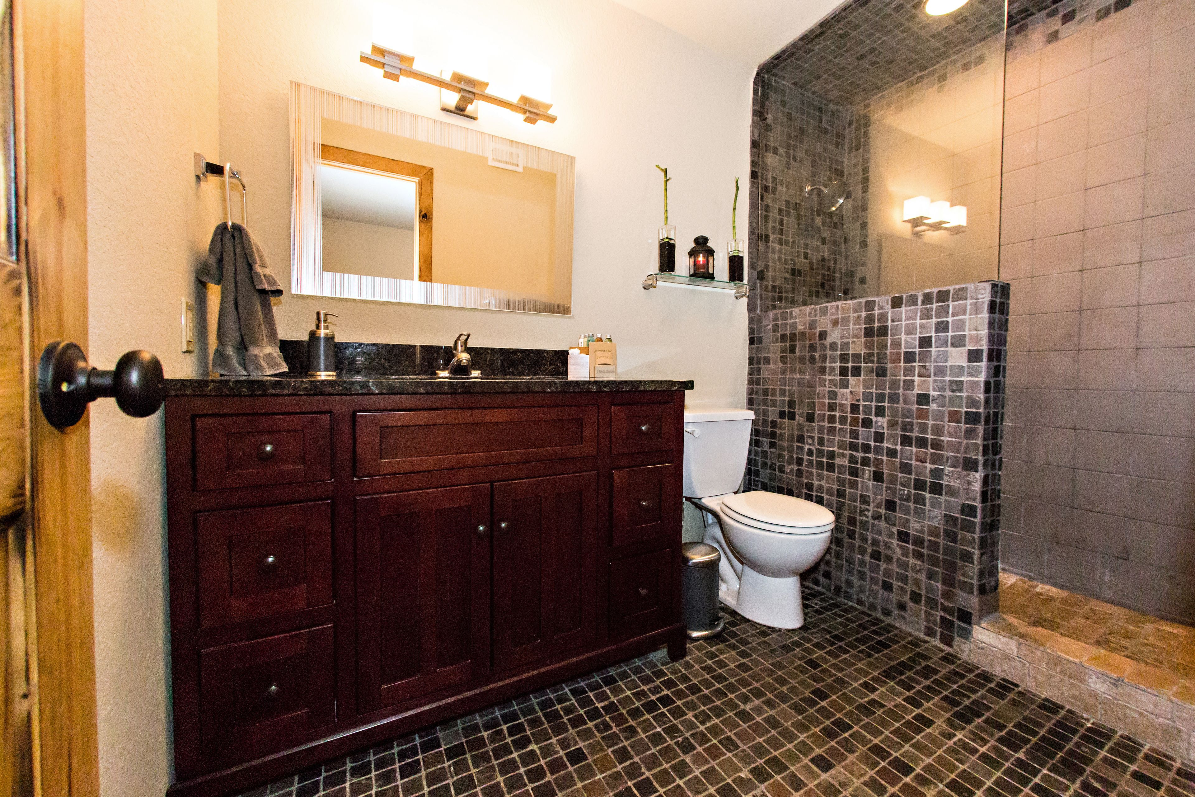 A bathroom with a dark wood vanity, a white toilet, and a glass shower enclosure.