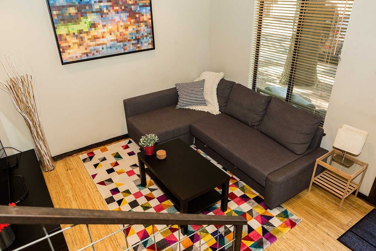 A living room with a sofa, a coffee table, a colorful rug, and a painting on the wall.