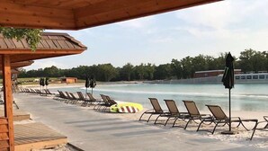 A beachside area with lounge chairs and umbrellas, a lifeguard stand, and a wooden deck. - 1700 South 2nd (Waco)