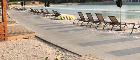 A beachside area with lounge chairs and umbrellas, a lifeguard stand, and a wooden deck.