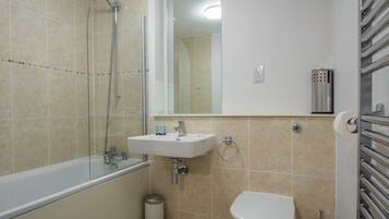 A modern bathroom with a bathtub, sink, toilet, and a glass shower enclosure.