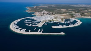 Vista aérea de una gran marina circular con numerosos barcos amarrados, rodeada de agua y tierra.