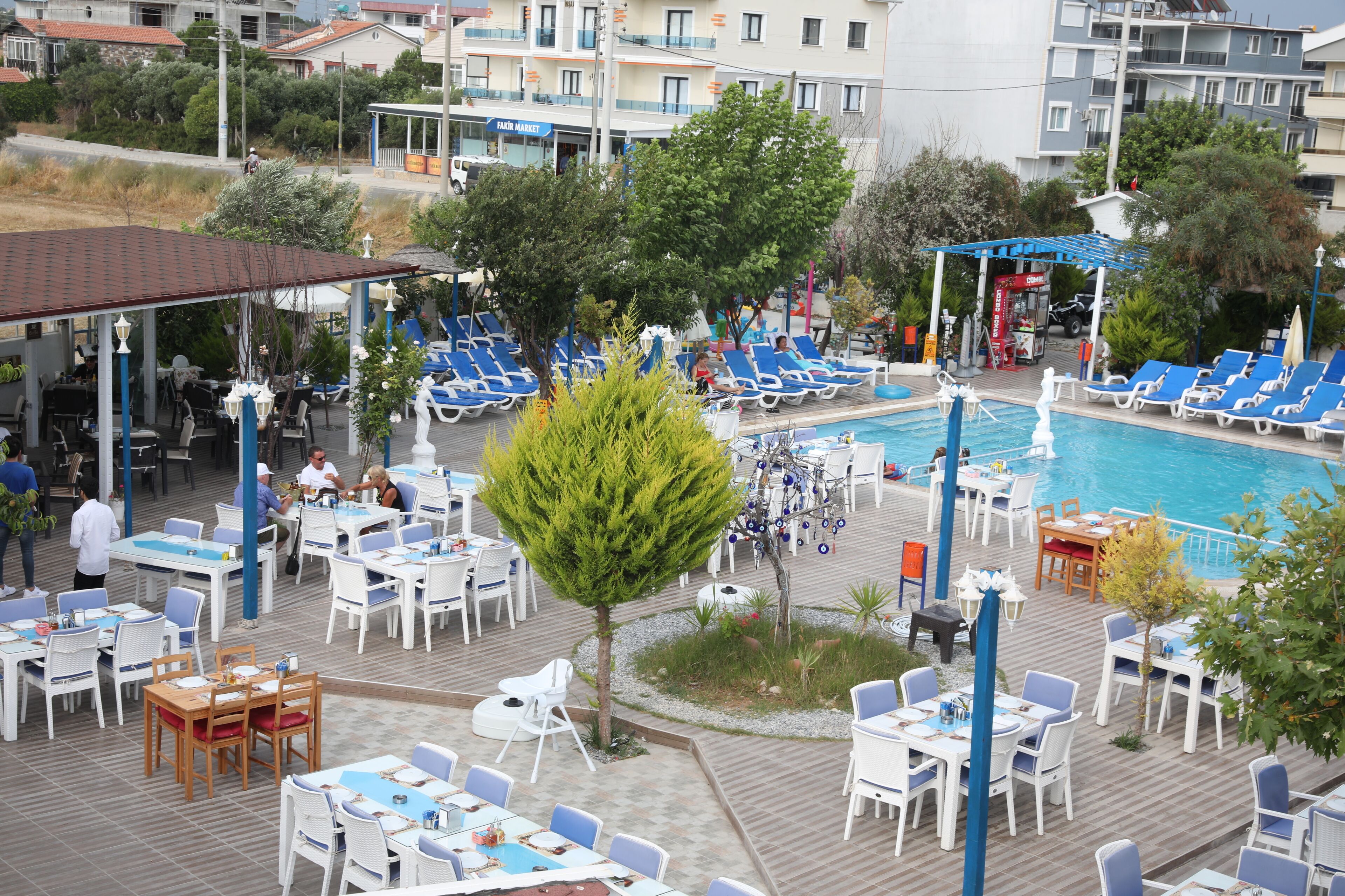 A poolside area with lounge chairs and tables, a swimming pool, and a covered seating area.