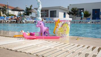 Zona de piscina con sillones de descanso, una estatua y un balde decorativo.