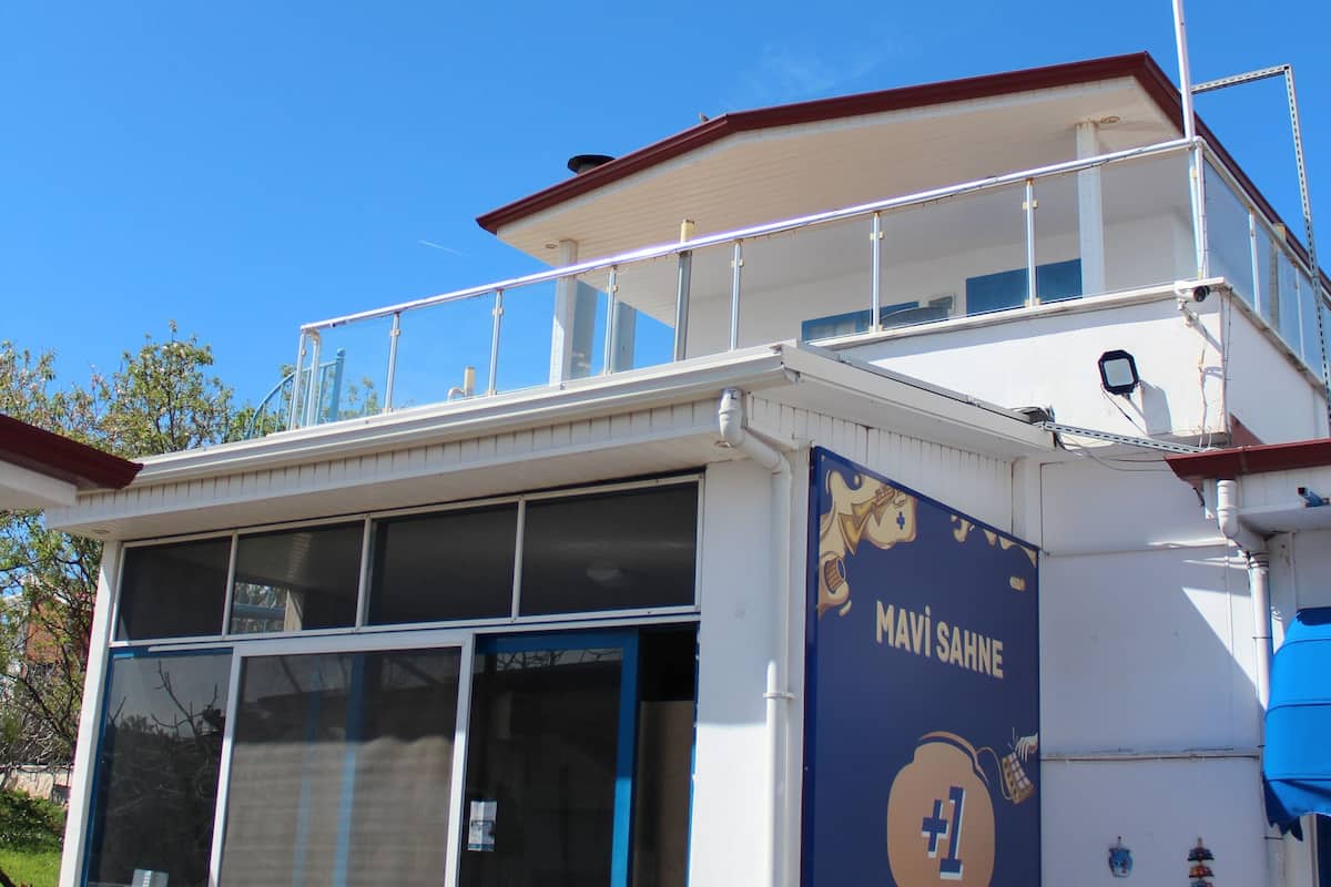 A building with a blue and white exterior, a balcony, and a sign that reads "MAVI SAHNE".
