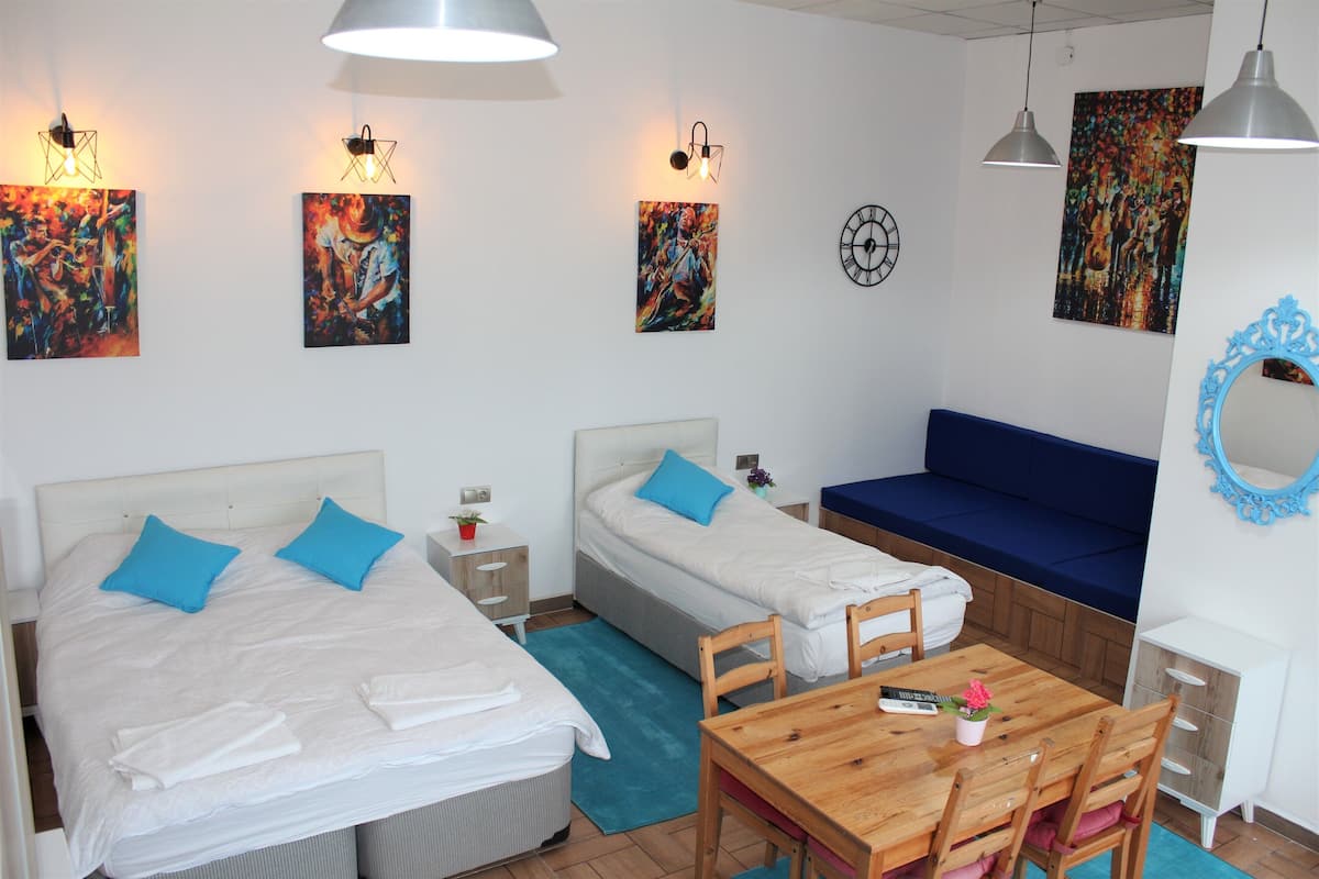 A hotel room with two beds, a wooden table, and a blue sofa.
