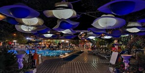 Ein Poolbereich im Freien mit einem außergewöhnlichen Deckenbauwerk, das große, blaue, schalenartige Strukturen zeigt.