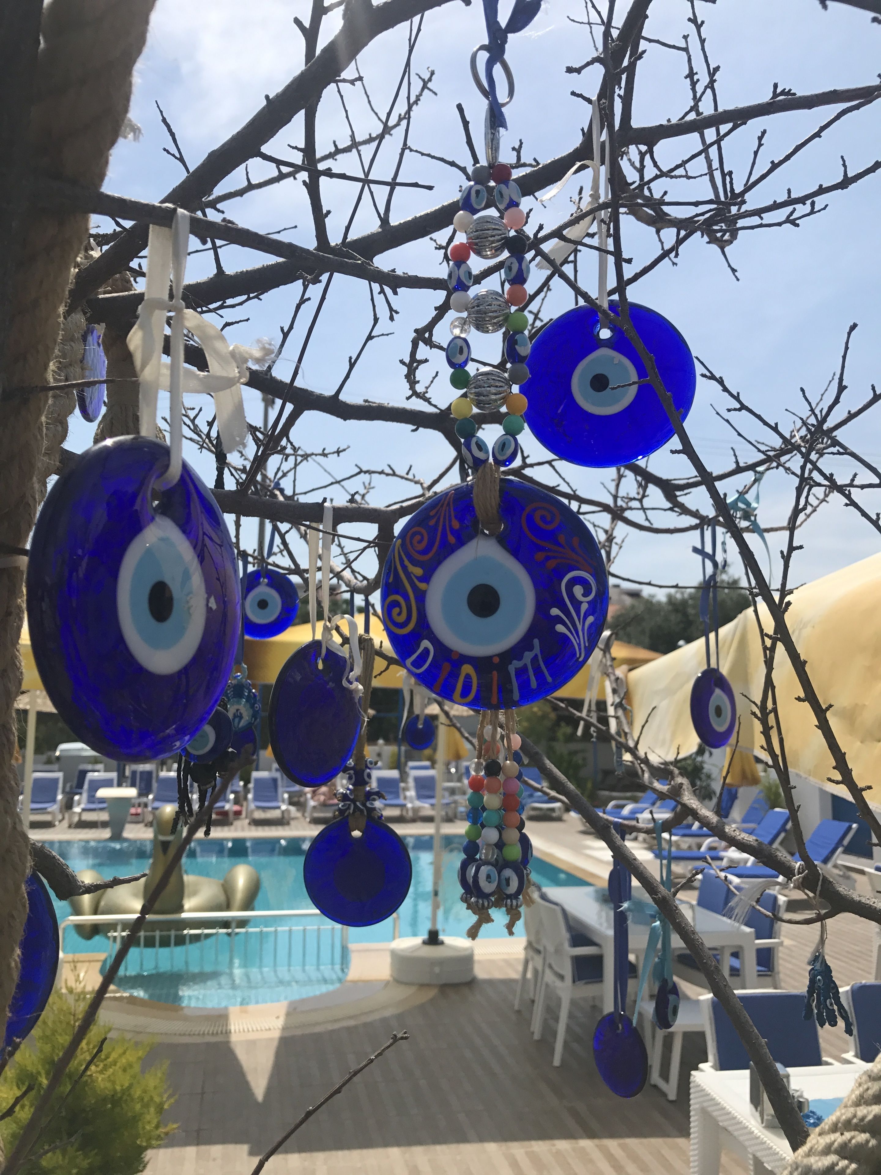 A poolside area with blue decorative items hanging from branches, lounge chairs, and a pool.