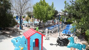 Zona de juegos infantiles con una casita azul, un tobogán y una bicicleta estática.