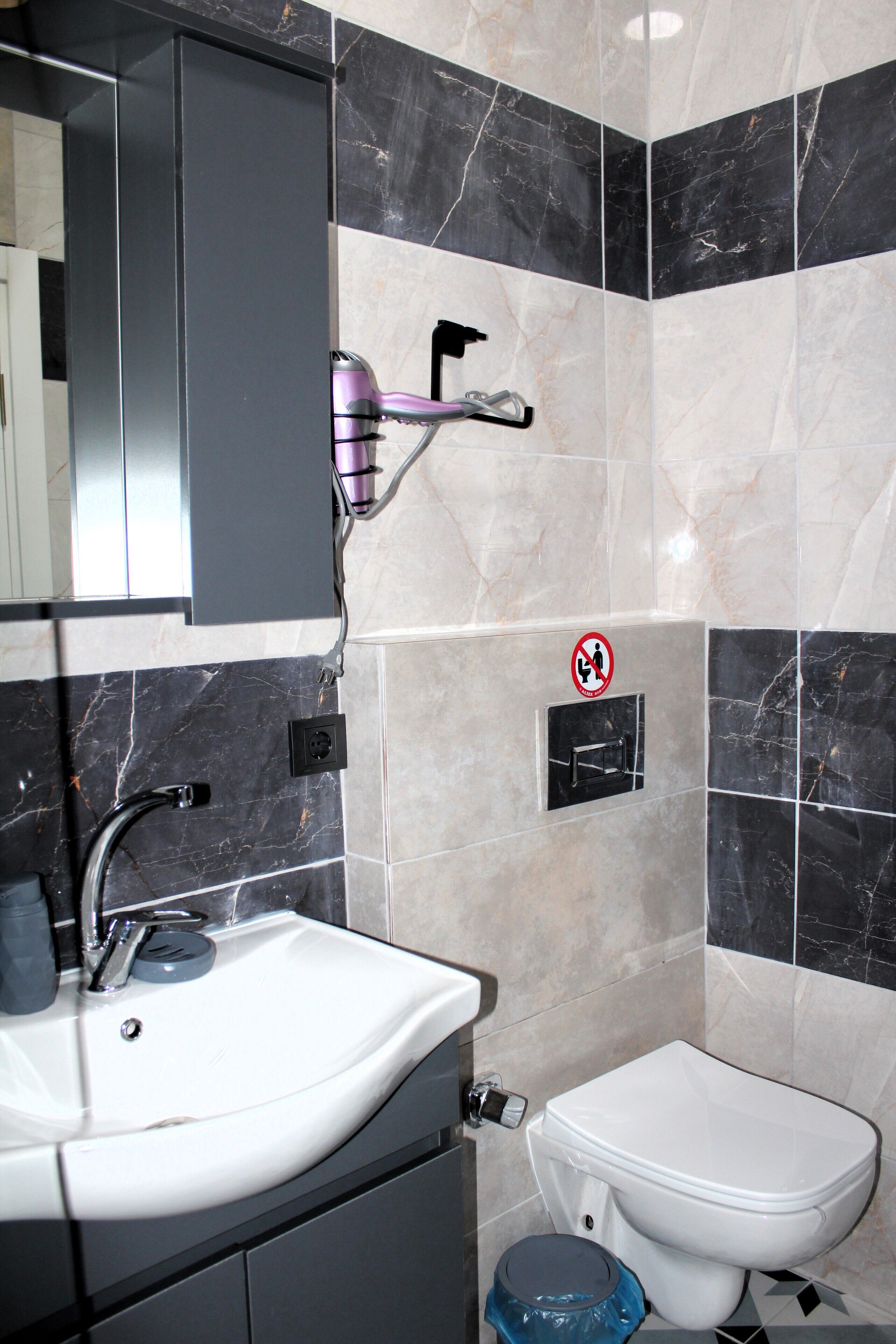 Une salle de bain avec un lavabo blanc, des toilettes et un miroir.