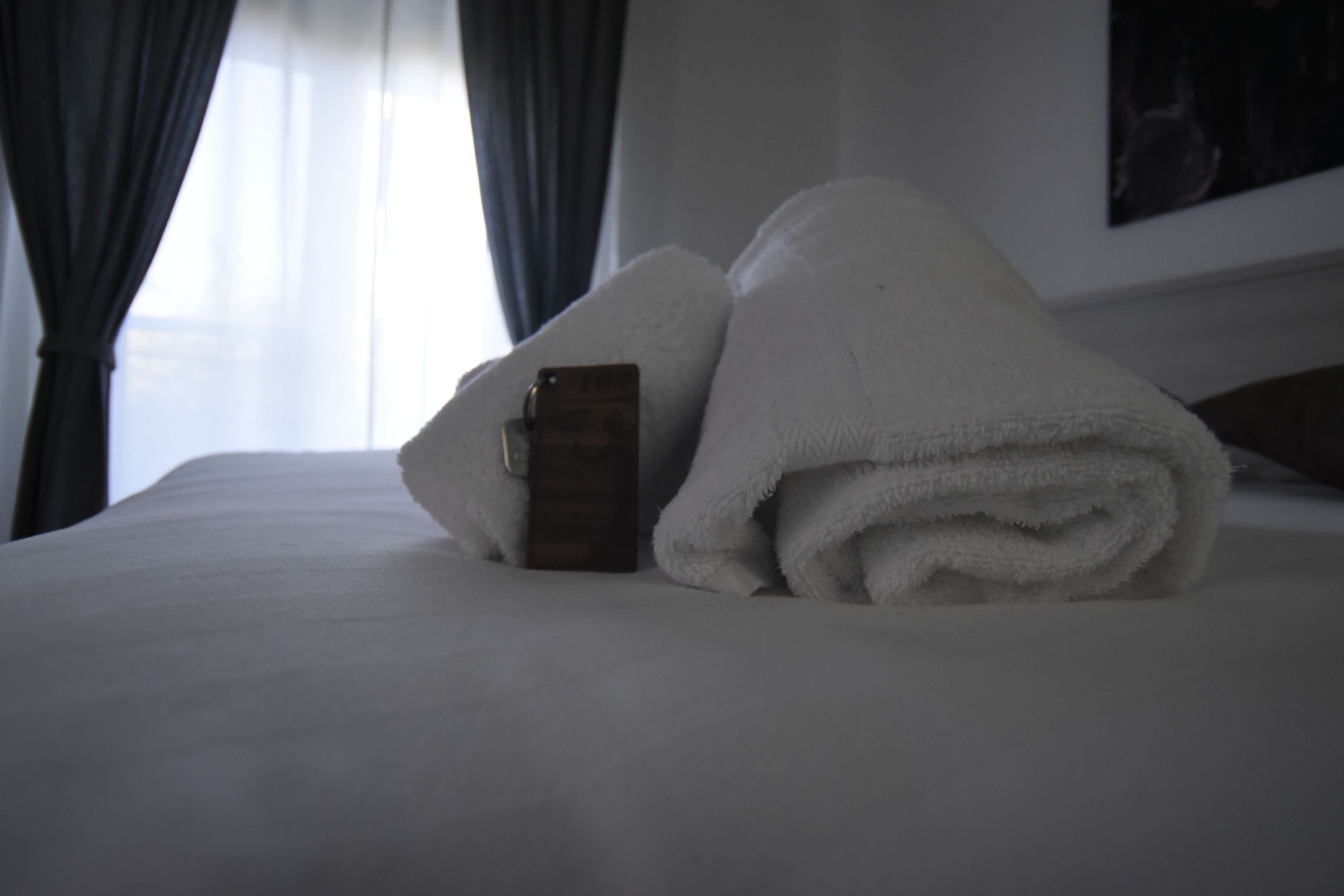 Una cama bien tendida con una toalla blanca doblada y un objeto de madera encima.