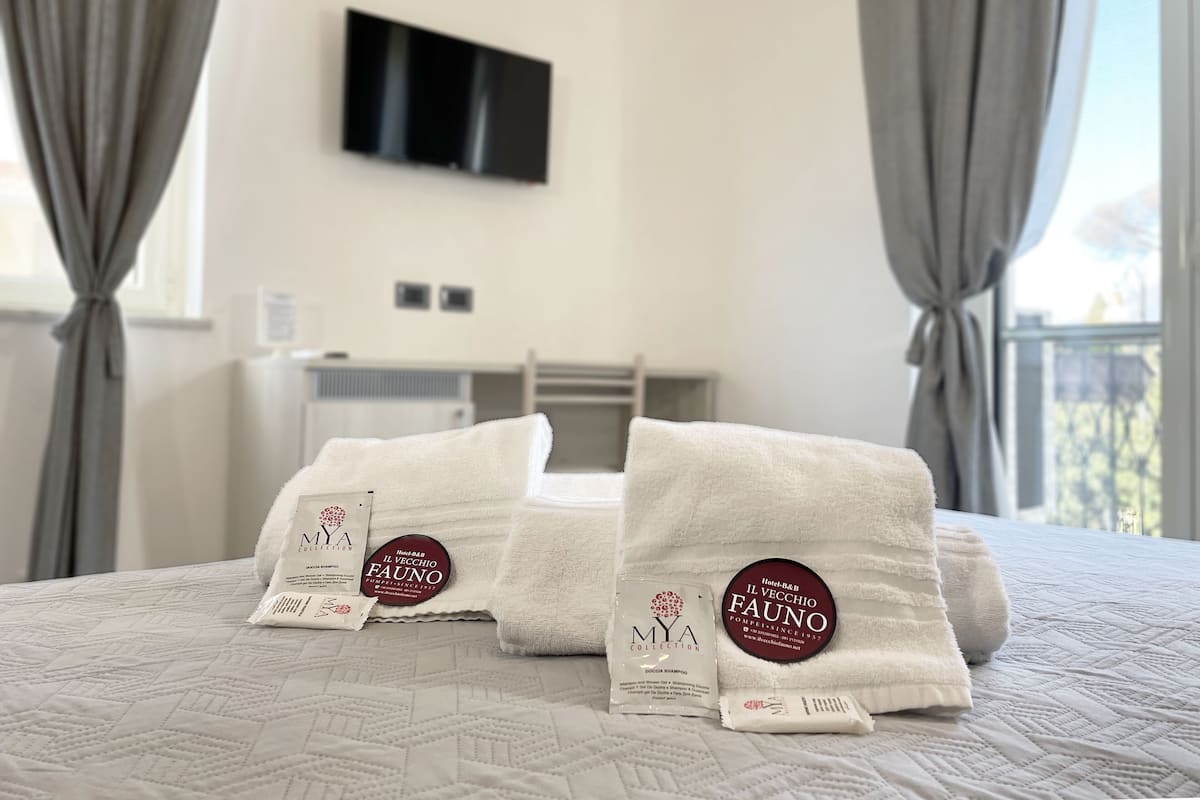 A hotel room with a bed, towels, and toiletries.