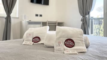A hotel room with a bed, towels, and toiletries.