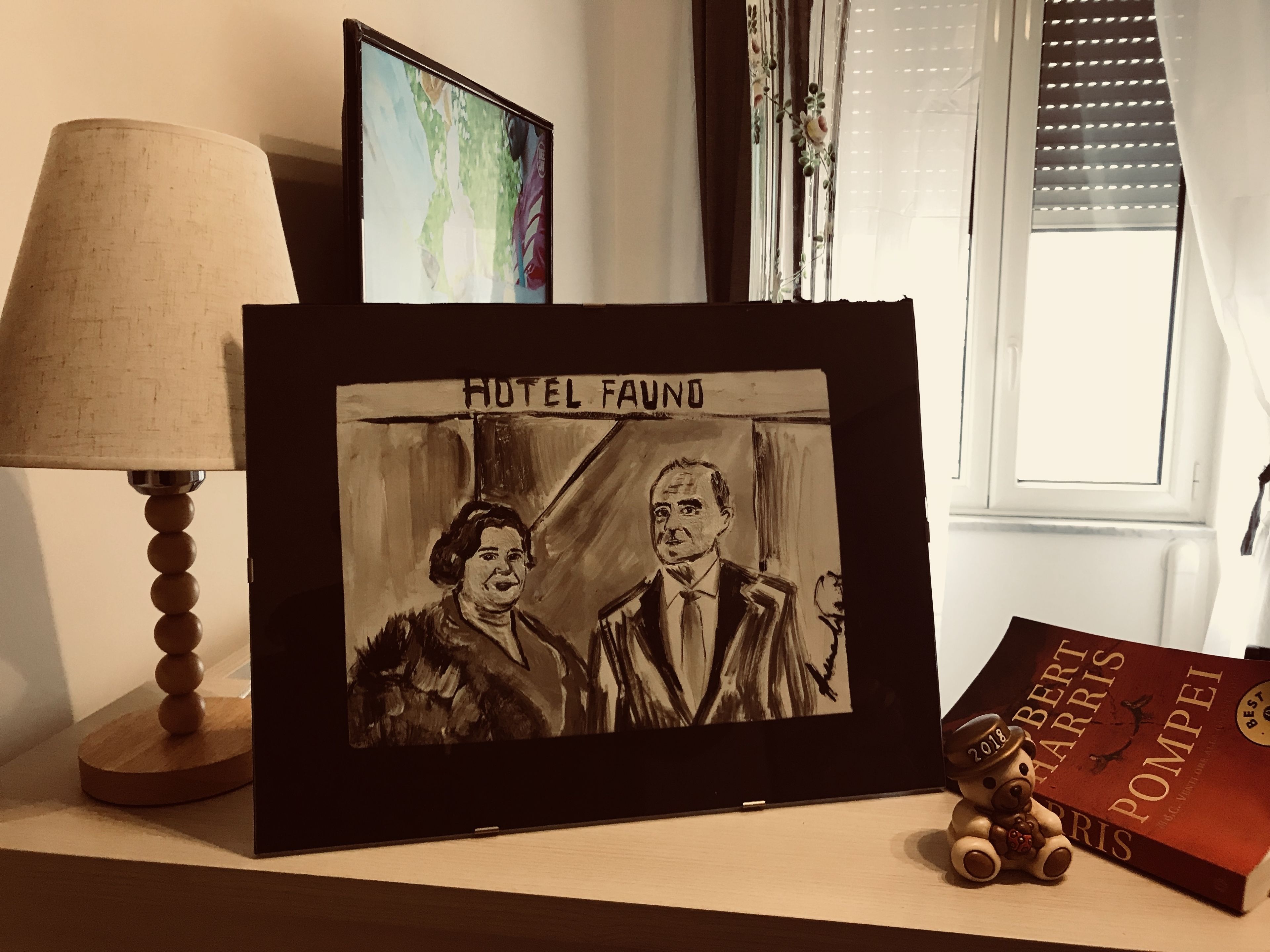 A framed artwork titled 'HOTEL FOUND' with a lamp and a book on a table.