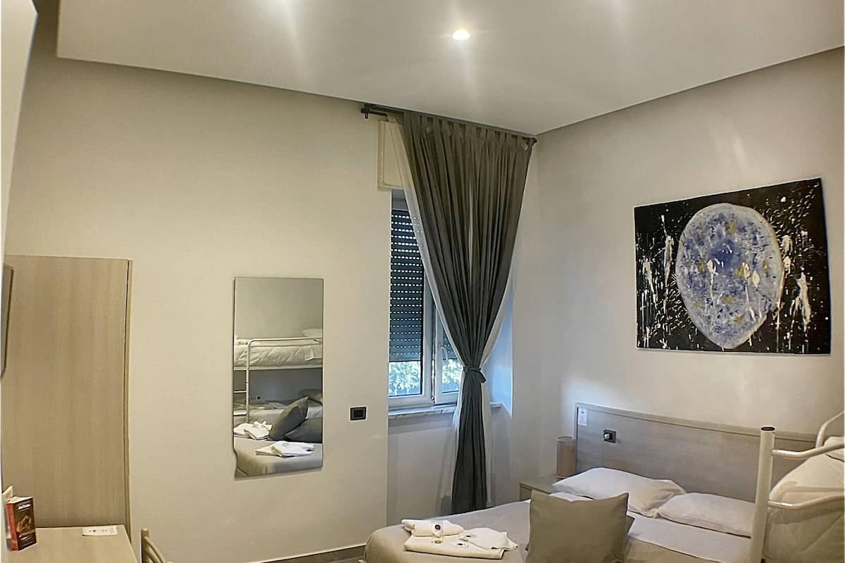 A modern hotel room with a bed, a desk, and a mirror.