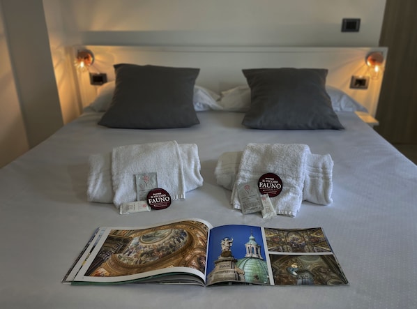 Una cama bien hecha con dos almohadas, un par de toallas y un folleto sobre la cama.