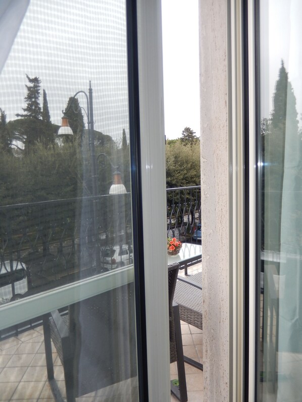 A view through a window with a metal railing, a table with chairs, and a potted plant. - Il Vecchio Fauno (Pompei)