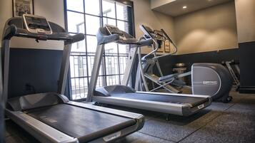 Un gimnasio con cintas de correr, una bicicleta estática y una máquina elíptica.