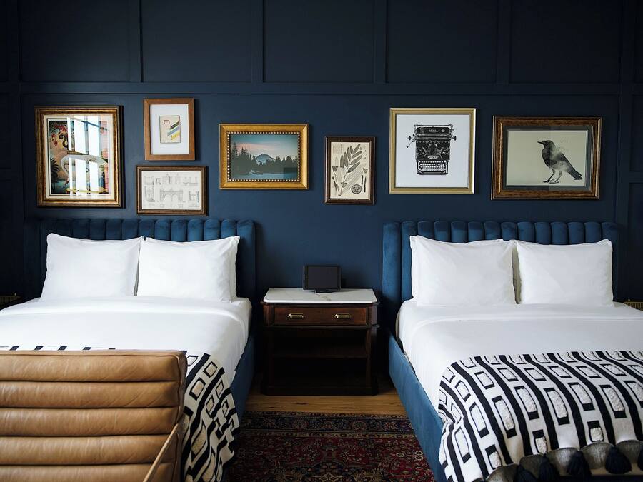 A hotel room with two beds, a chest of drawers, a nightstand, and a large rug.