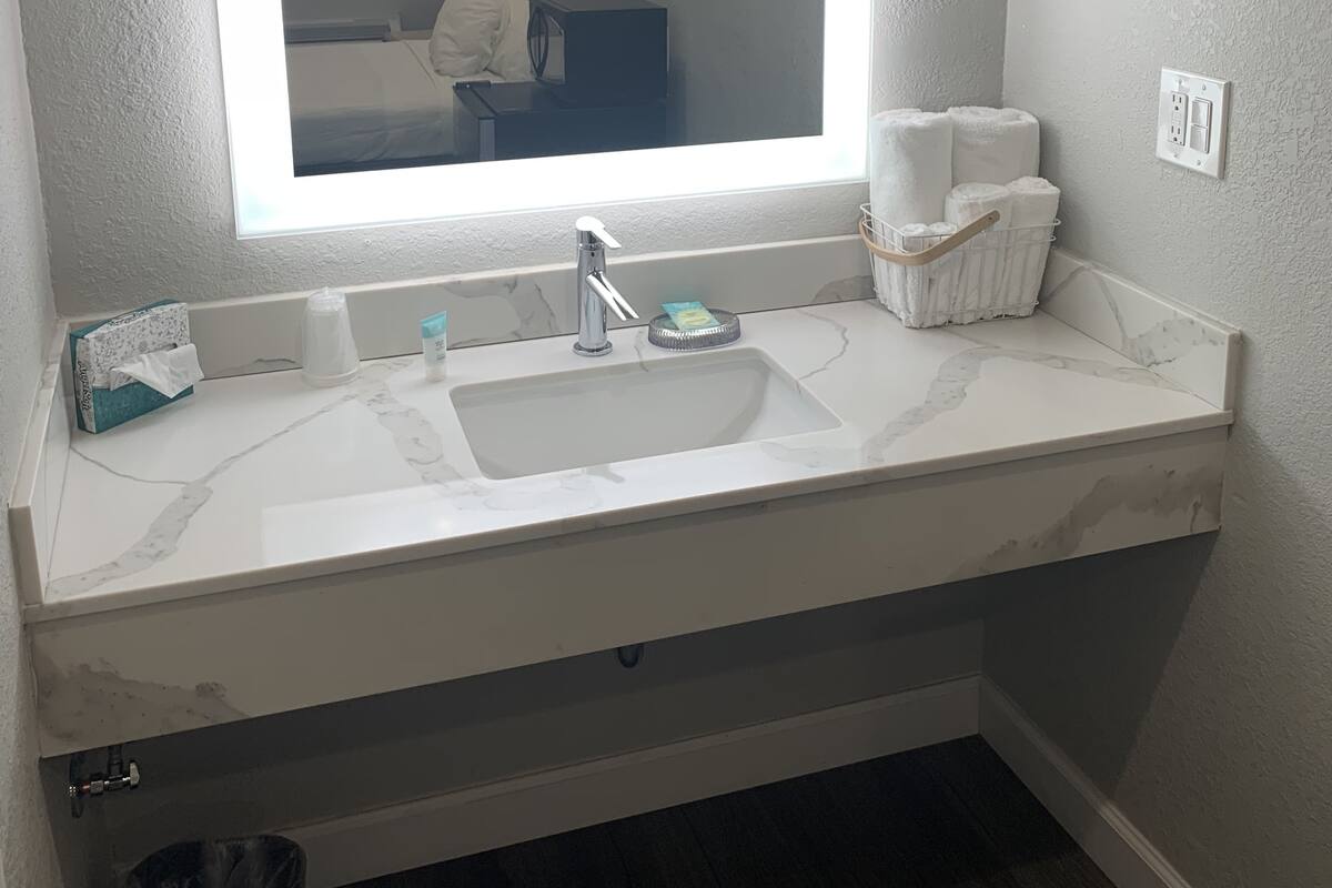 Ein Badezimmer mit einem großen Spiegel, einem Waschbecken, einer Toilette und einem Mülleimer.