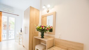 A modern bathroom with a wooden vanity, a mirror, and a vase of flowers. - Mastorakis Studios (Hersonissos)