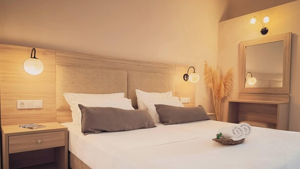 A modern hotel room with a large bed, two bedside tables, a nightstand, and a mirror. - Mastorakis Studios (Hersonissos)