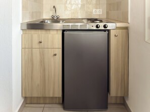A compact kitchen with a built-in stove, sink, and refrigerator. - Mastorakis Studios (Hersonissos)