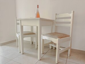 A white table and chair set in a room with tiled flooring. - Mastorakis Studios (Hersonissos)