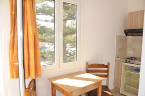 A small kitchen with a window, a table, and a chair. - Mastorakis Studios (Hersonissos)