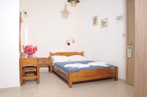 A neatly arranged bedroom with a wooden bed, a bedside table, a small desk, and a chair. - Mastorakis Studios (Hersonissos)