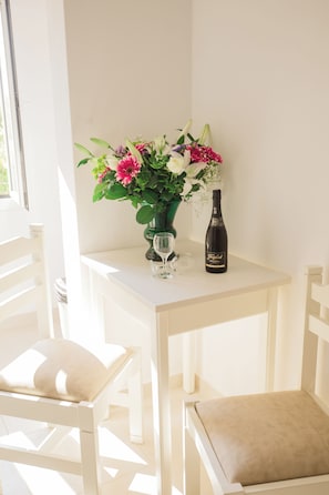 Une table blanche avec un vase de fleurs et une bouteille de vin.