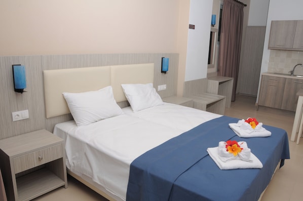 A hotel room with a bed, bedside tables, a nightstand, a bathroom with a sink, and a wardrobe. - Mastorakis Studios (Hersonissos)