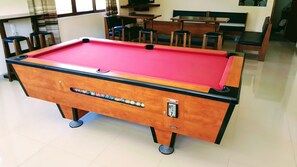 A pool table with a red felt surface, wooden frame, and a label indicating 'POOL BILLIARDS.' - Mastorakis Studios (Hersonissos)