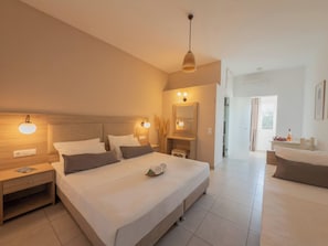 Una habitación de hotel moderna con una cama grande, mesitas de noche, un tocador con espejo y un baño con bañera.
