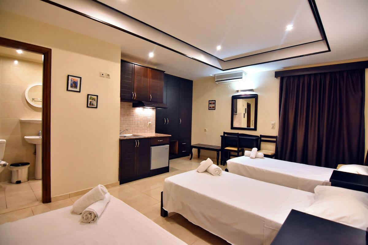 Une chambre d’hôtel avec deux lits, une salle de bain, un coin cuisine et un bureau.