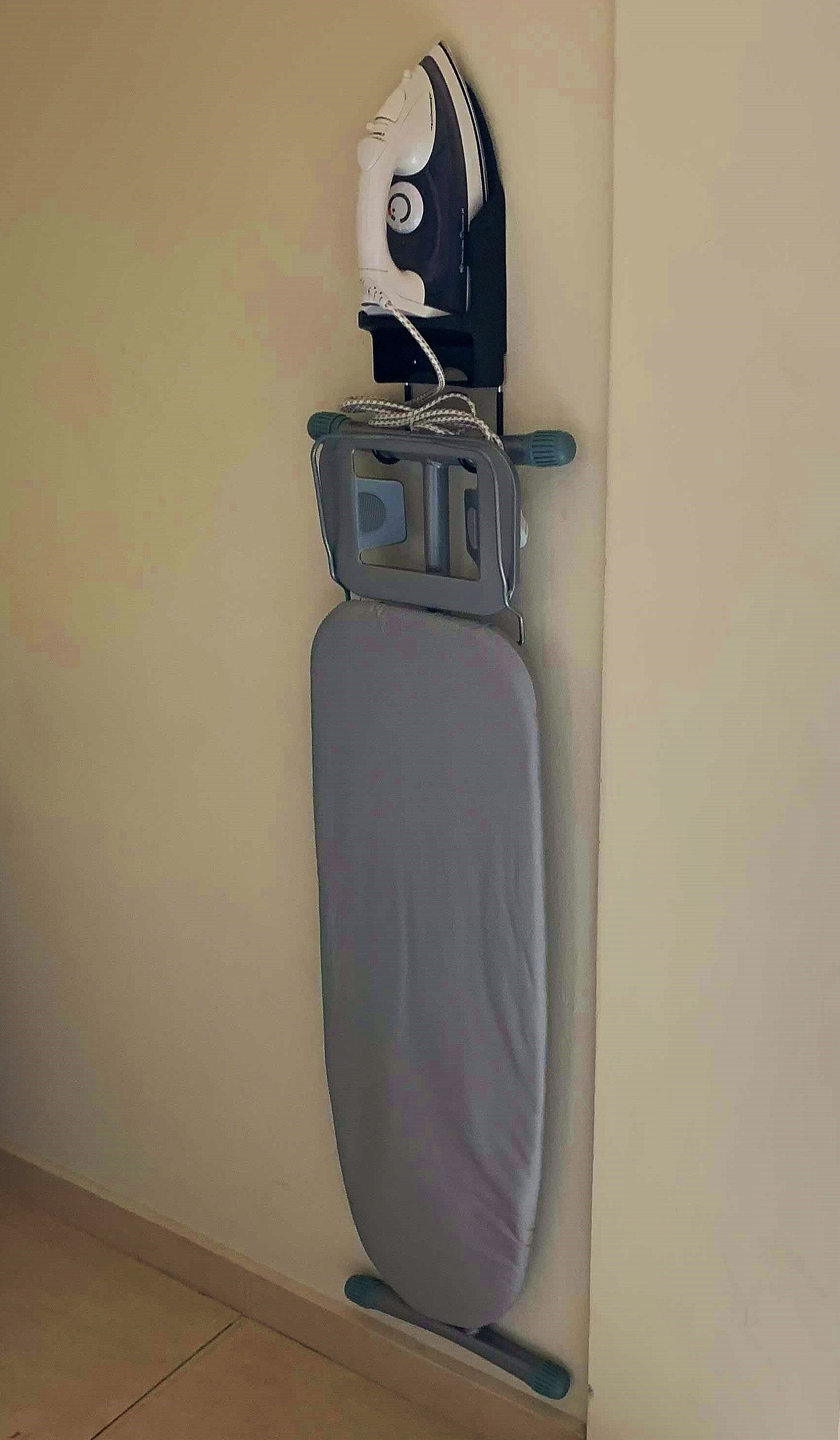 A wall-mounted ironing board with an iron and a cloth.