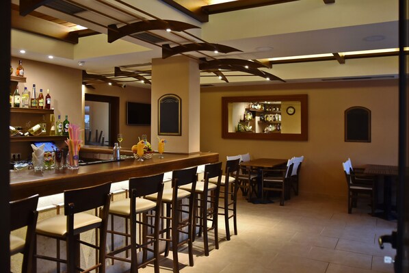 Una zona de bar con sillas de madera, una barra con botellas y un reloj en la pared.