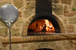 Un four à pizza en briques, avec une pelle à pizza en métal devant.
