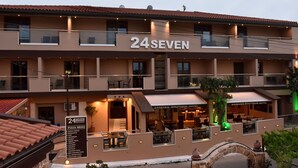 Un hôtel à plusieurs étages, avec une enseigne indiquant « 24SEVEN » et un menu de pizzas.