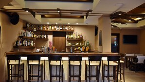 Un espace bar doté de plusieurs étagères remplies de bouteilles d’alcool, d’un comptoir et de plusieurs tabourets de bar.