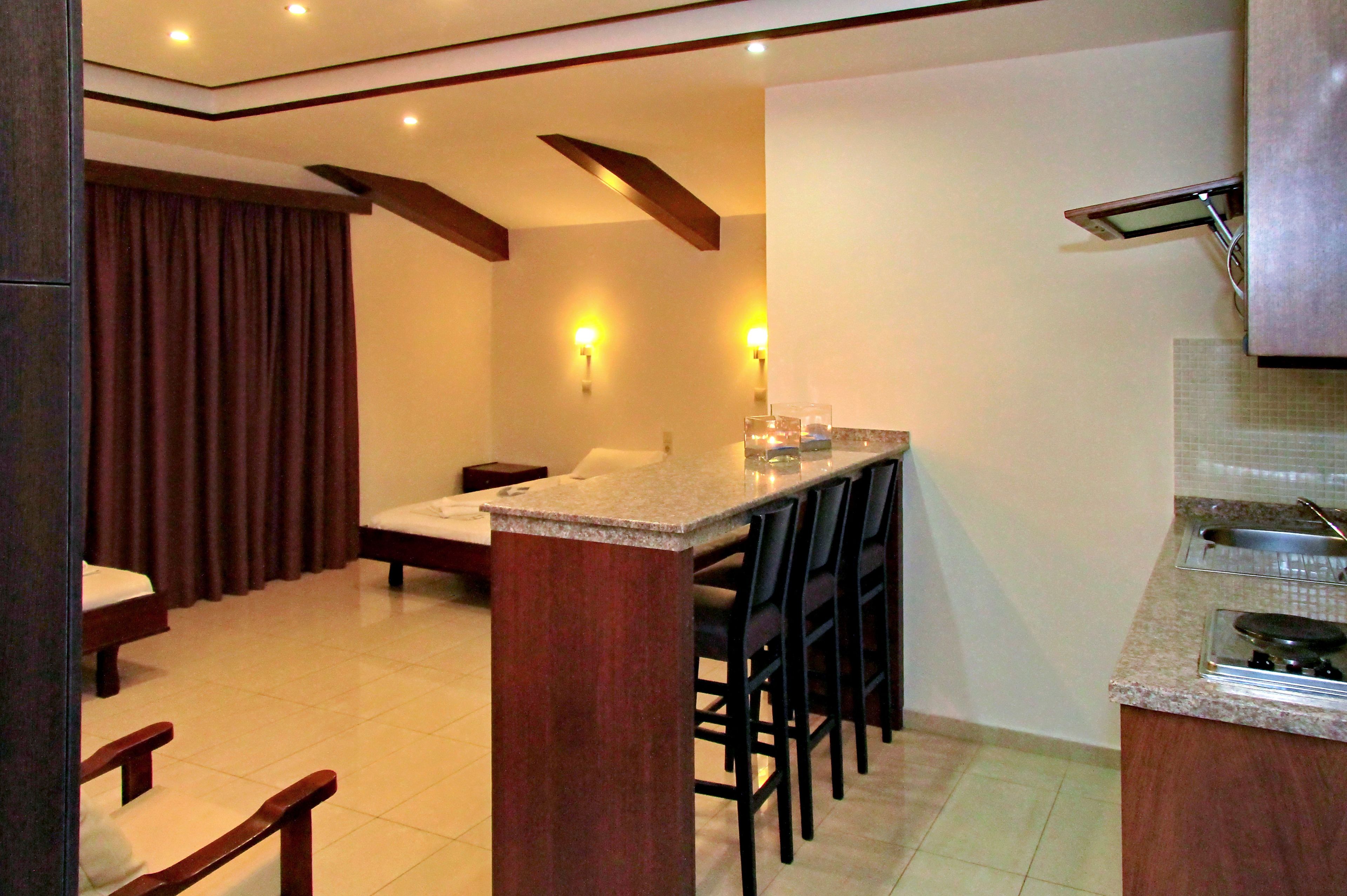 A compact kitchen with a dining area, featuring a kitchen island, bar stools, and a built-in stove.