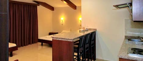 A compact kitchen with a dining area, featuring a kitchen island, bar stools, and a built-in stove.