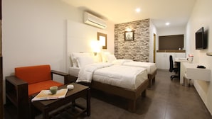 A hotel room with two beds, a desk, a chair, a TV, and a bathroom. - Hotel Casa (Vadodara)